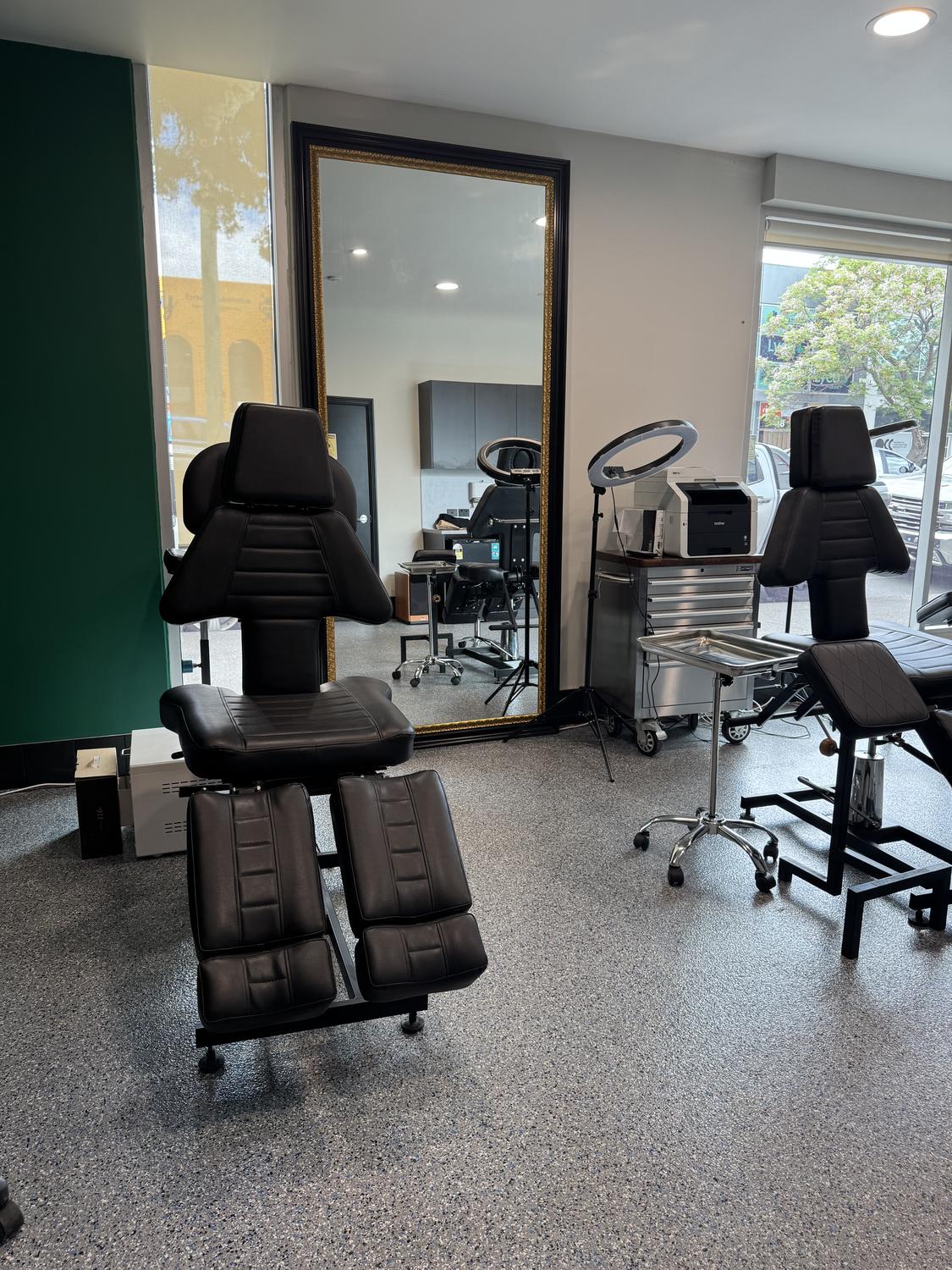 A tattoo chair beside the full-length gilt mirror in the studio