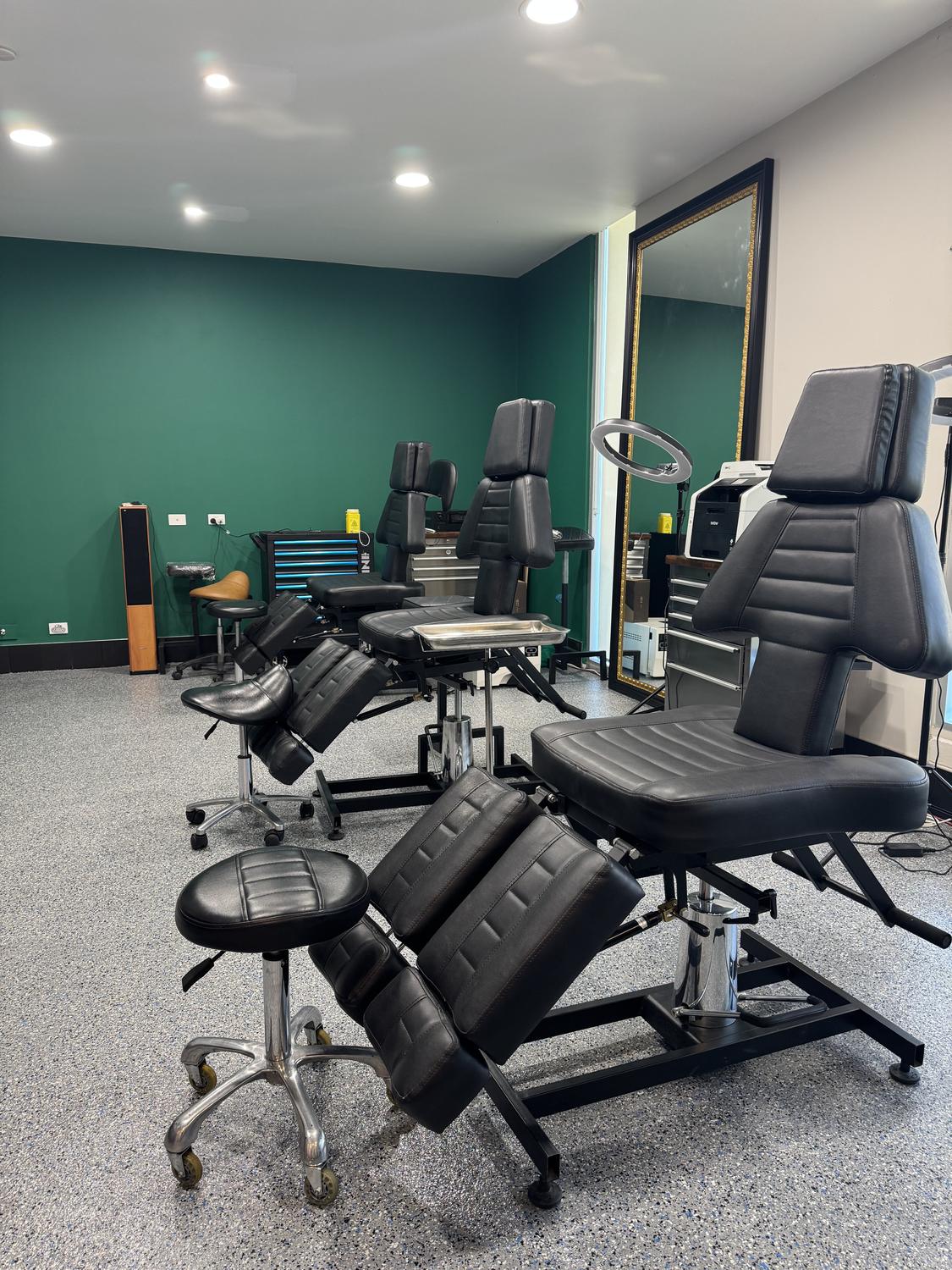 The main floor at Mother Goose Tattoo, Kensington — chairs against the green wall